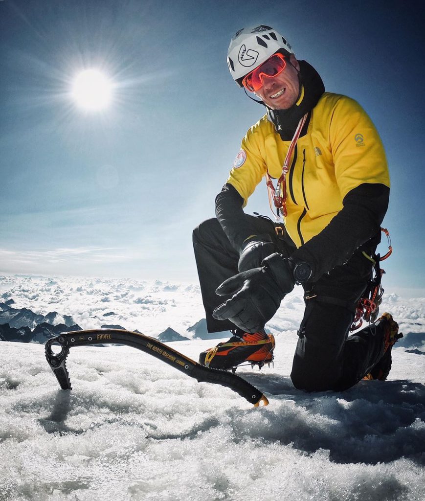 alpinist posint at the peak of the mountain with ice axe the dark machine gravel